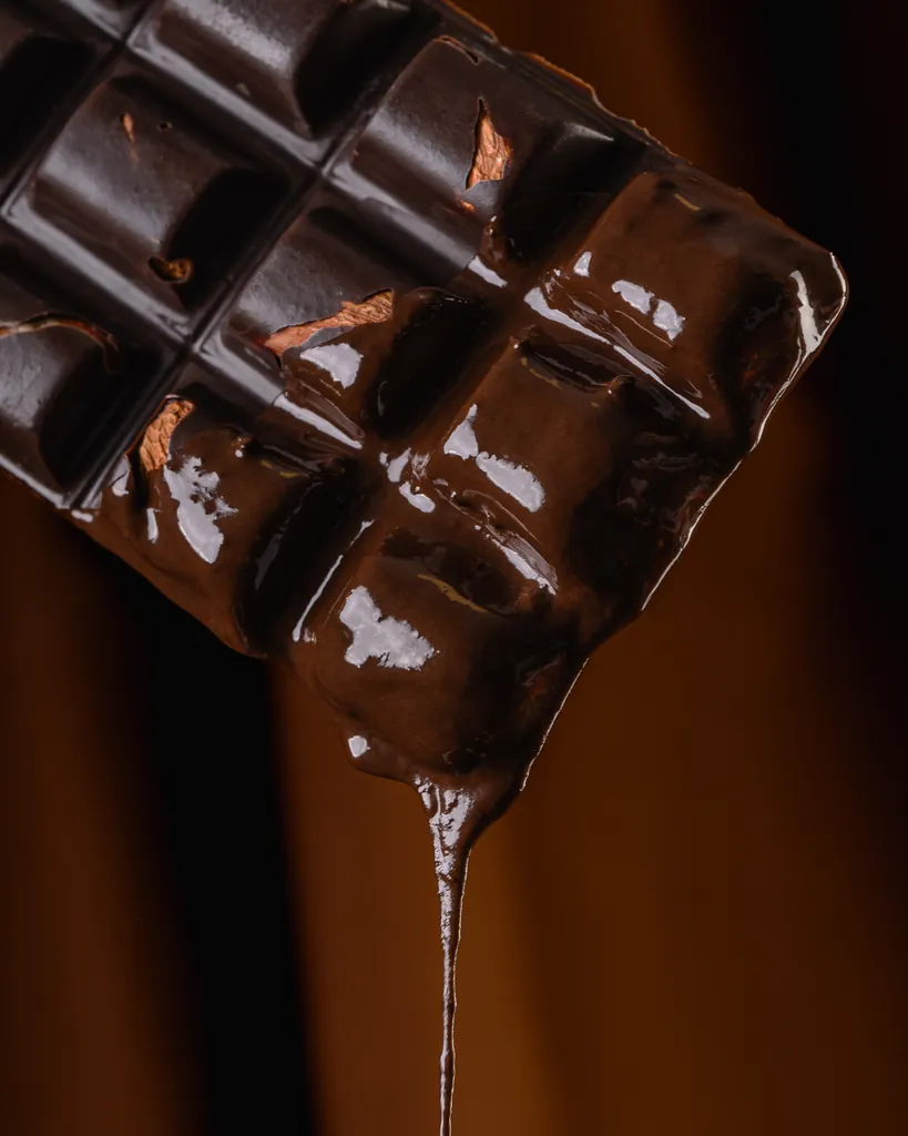 Una tableta de chocolate Malfatti con almendras, con chocolate derretido que gotea desde abajo.